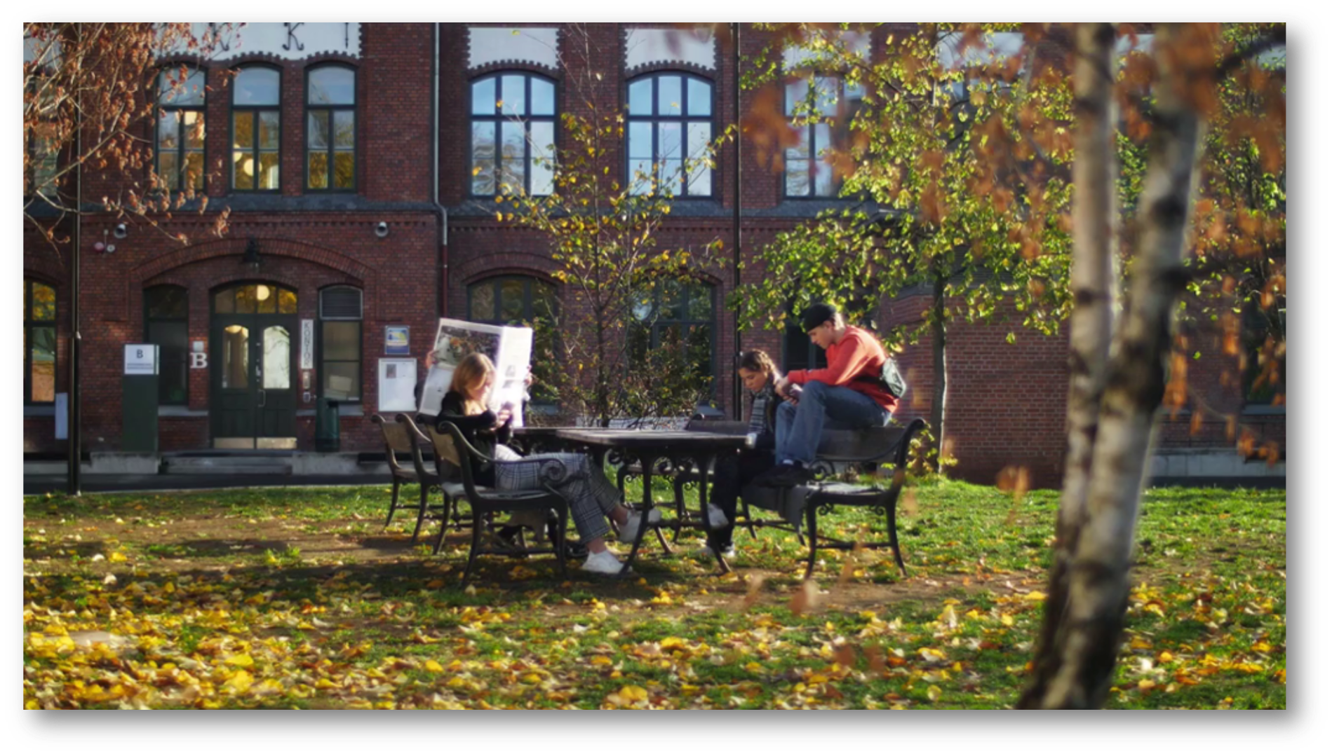 Tre ungdommer sitter ved et bord i en park